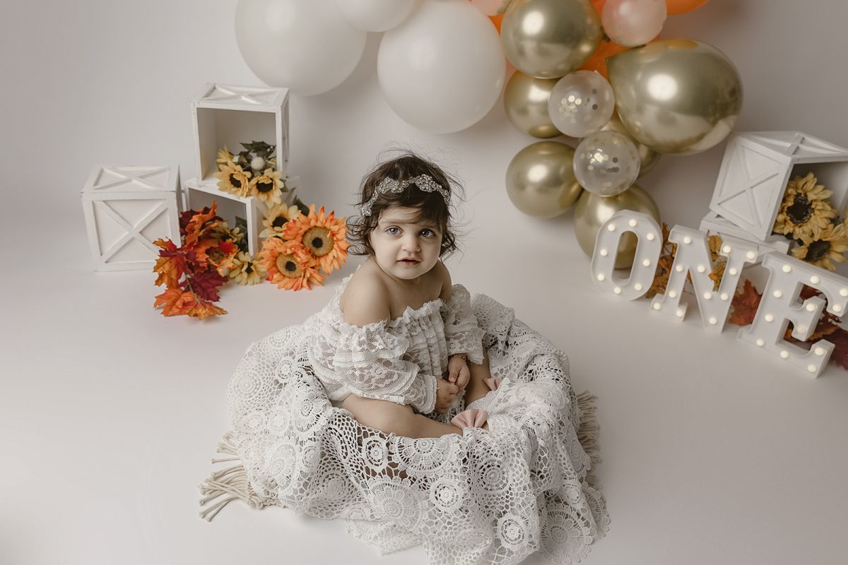Baby girls first birthday pictures with sunflowers and white lace outfit