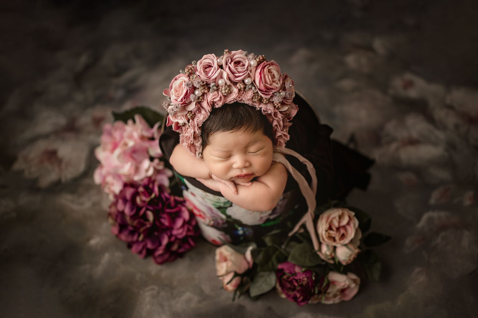 Newborn baby peacefully posed in a rustic bucket, captured in a fine art studio session by newborn photographer White Lavender Photography in Dallas