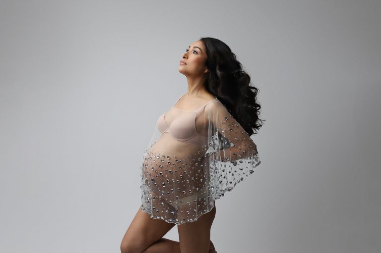 Elegant in-studio maternity portrait of an expecting mother in a designer gown, captured by White Lavender Photography in Dallas