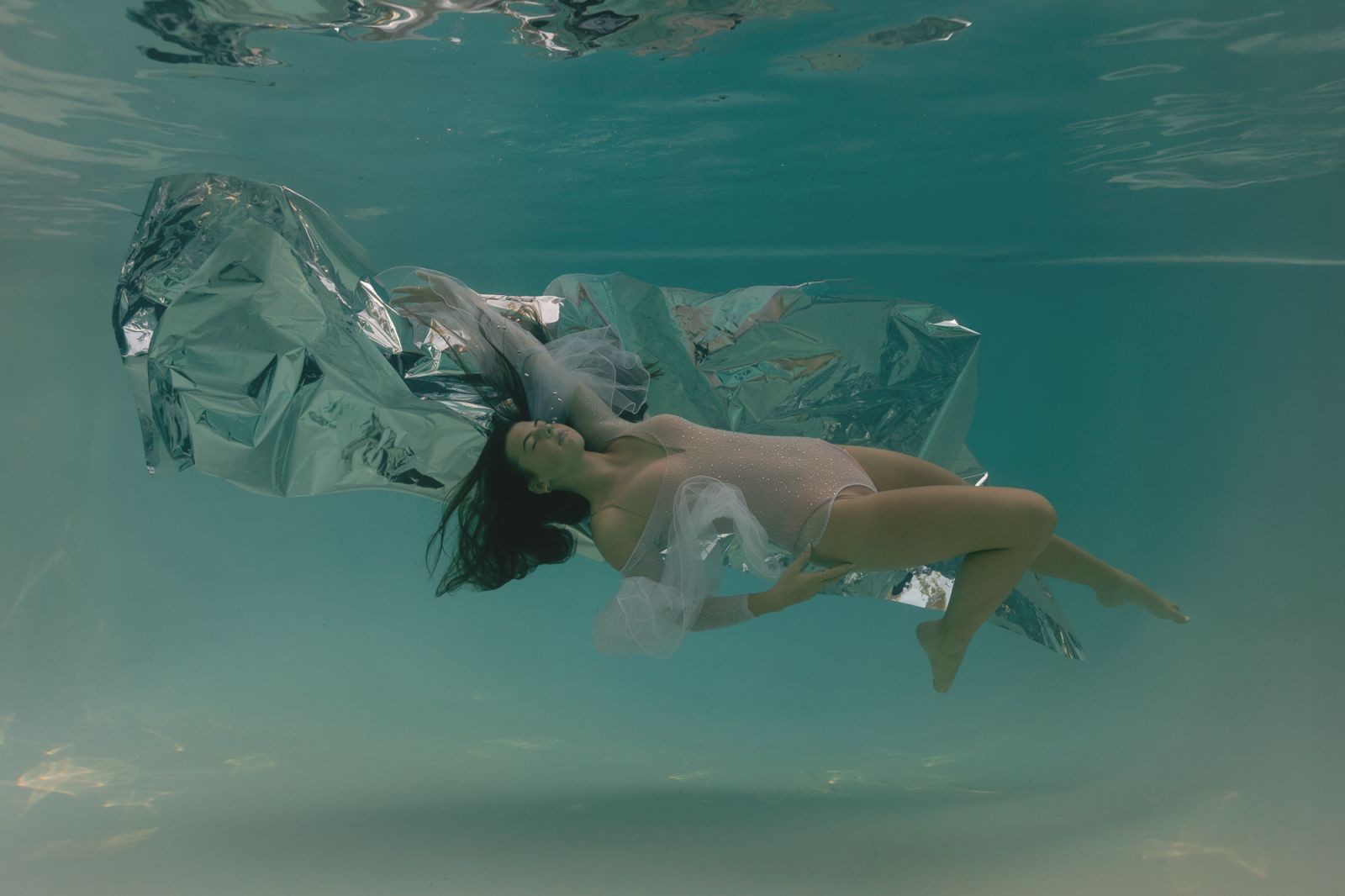 Fine-art underwater maternity portrait with metallic silver fabric and elegant pose — artistic underwater photography by White Lavender Photography in Dallas–Fort Worth