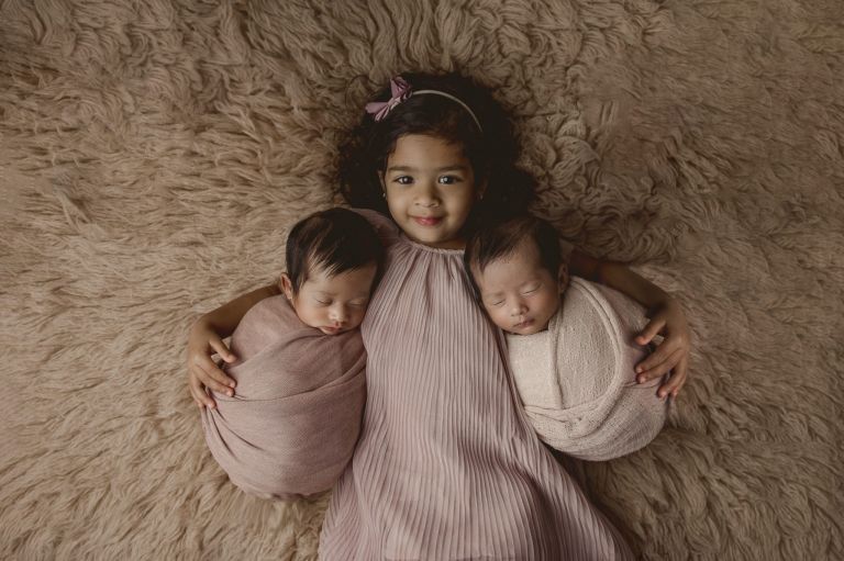 Newborn twins photographed together with sibling during a thoughtfully paced session
